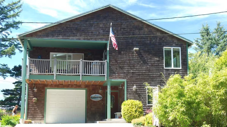 A brown house with green details and an American flag