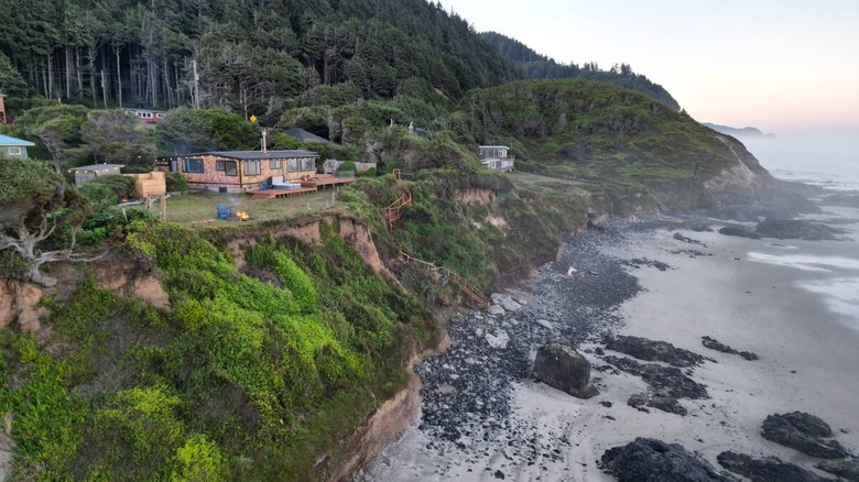 Shore of an ocean with a house along a hillside in the background