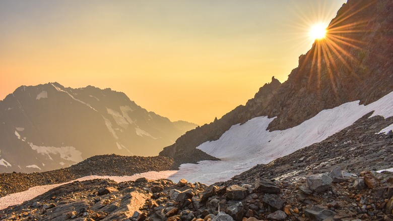 A glacier on a mountain top with the sun setting behind