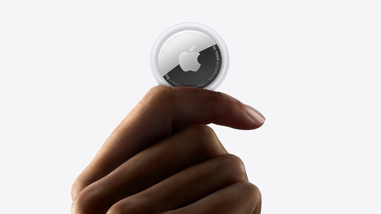 A hand holding an Apple AirTag.