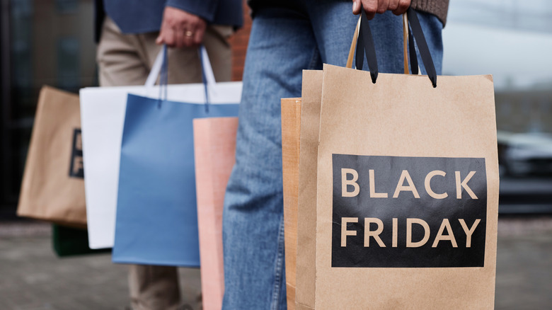 Two people holding shopping bags, one bag imprinted with "Black Friday."