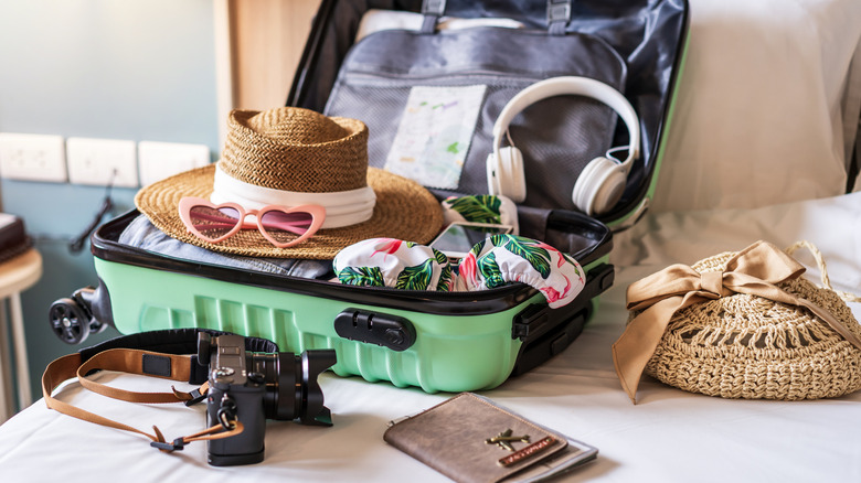 A suitcase full of traveler accessories, like headphones, sunglasses, hat, etc.