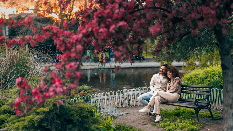 A couple relaxing by a pond in the spring.