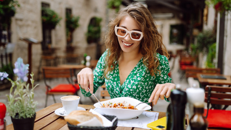 Portrait of a smiling woman eating pasta at cozy Italian restaurant outdoors