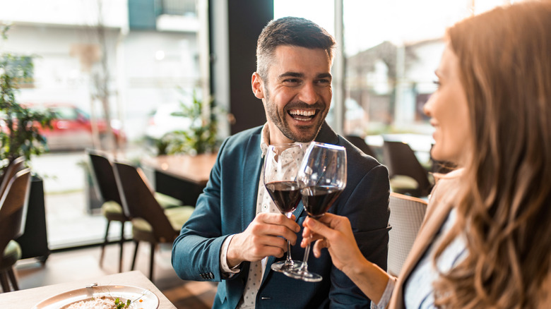 man toasting wine with woman in a restaurant during lunch