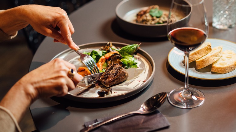 Close-up of diner cutting into steak