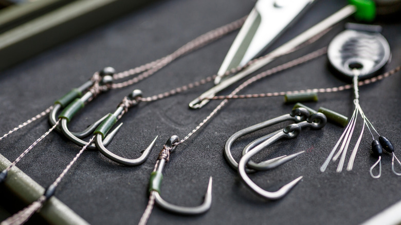 Metal fishing hooks, a line cutter, and other tackle materials sitting on a tray