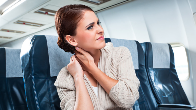 woman rubbing neck on plane