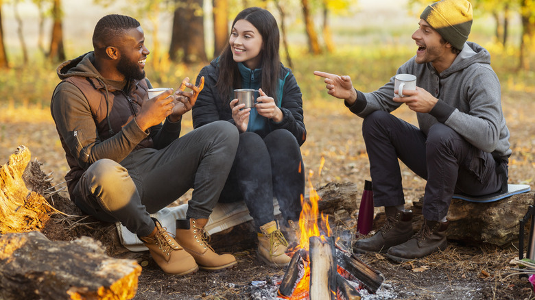 friends drinking coffee around campfire