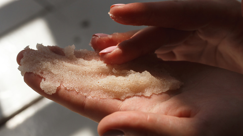 Hands rubbing body scrub in the sunlight.