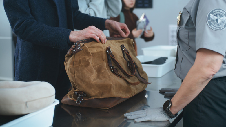 Security officer checking a bag at the airport counter