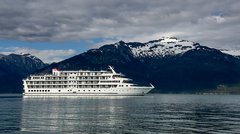 A smaller cruise ship in front of mountains in Alaska.