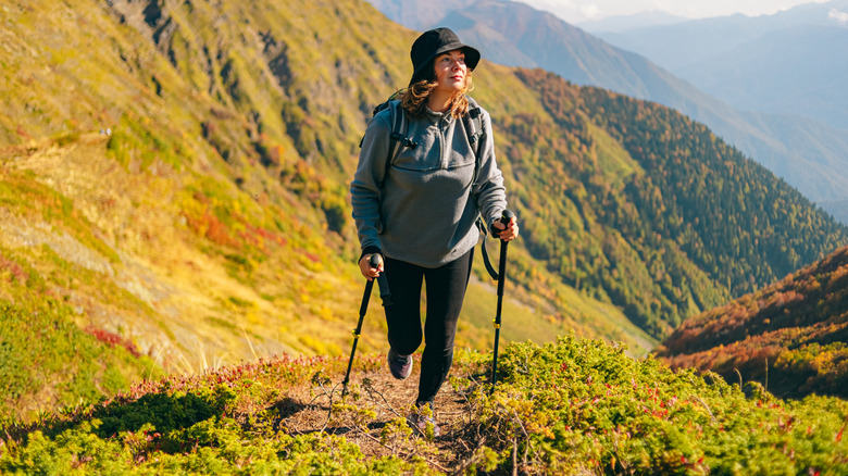 Female hiker holding trekking poles while hiking