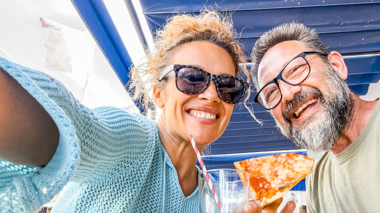 cheerful man and woman enjoying pizza in selfie