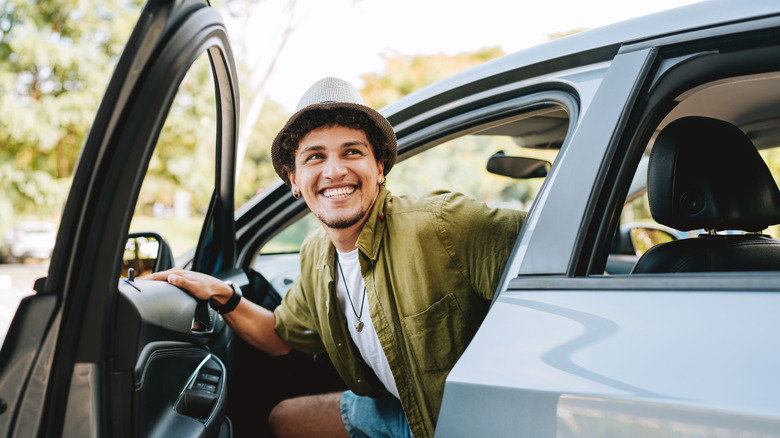 A person opening a car door while smiling