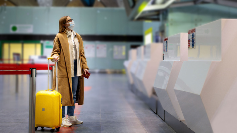 Woman with luggage wearing mask