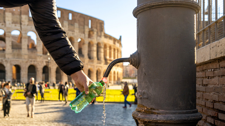 Person fills water bottle outside the Colosseum