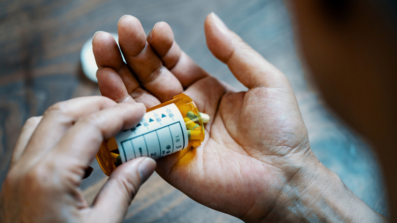 Hand holding pills and pill bottle