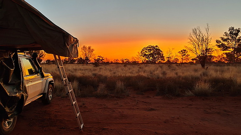 camping in the outback of Australia while the sun goes down over the bush