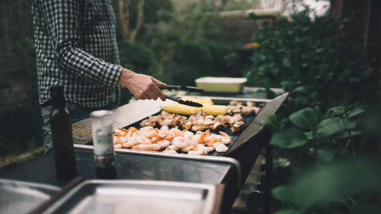 Man grilling meat and seafood on an outdoor barbecue.