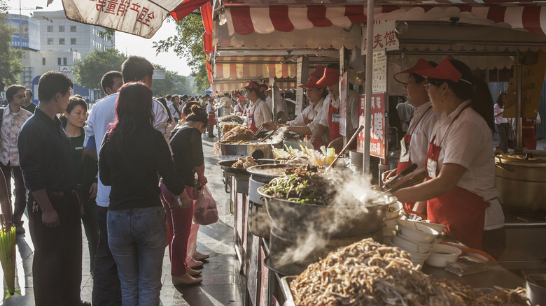 Customers buying food at the Donghuamen Snack Night Market, a large outdoor market at the north entrance of Wangfujing Street in Beijing.