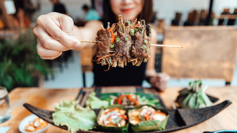 Close-up shot of young Asian woman having freshly made authentic Thai food in a restaurant