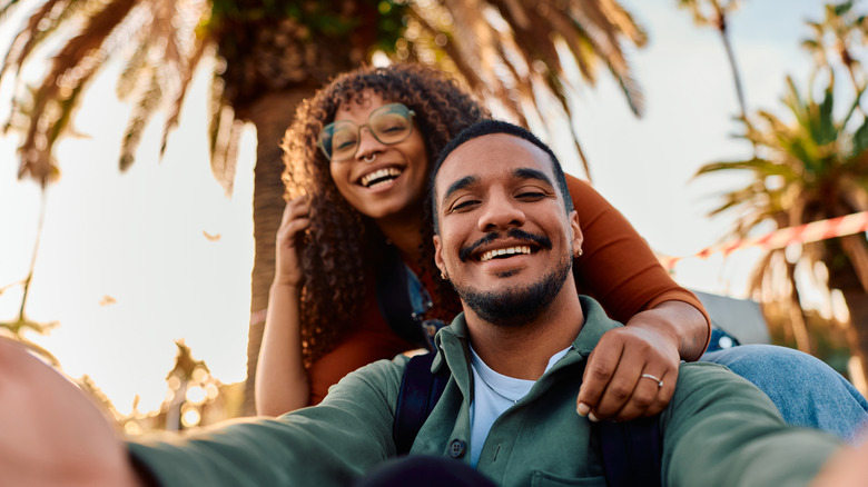 A smiling couple with palm trees.
