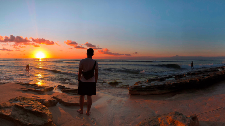 A man watches the sunset at Balangan Beach in Bali, Indonesia