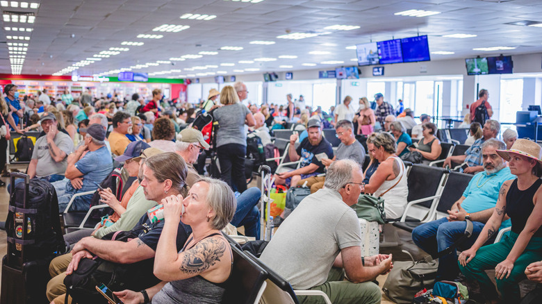 Passengers wait in an airport departure lounge.