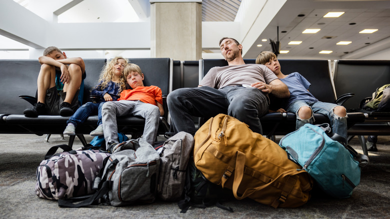 A family of five sleep on seats in an airport departure lounge.