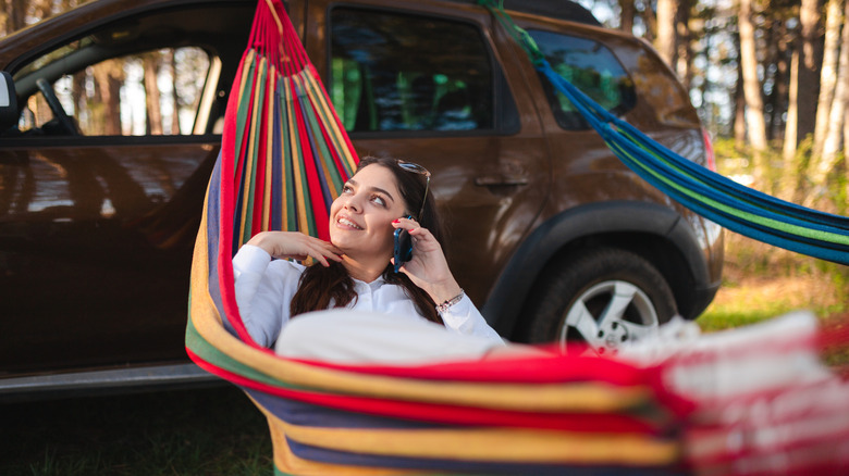 A woman relaxing in a hammock held up by a car
