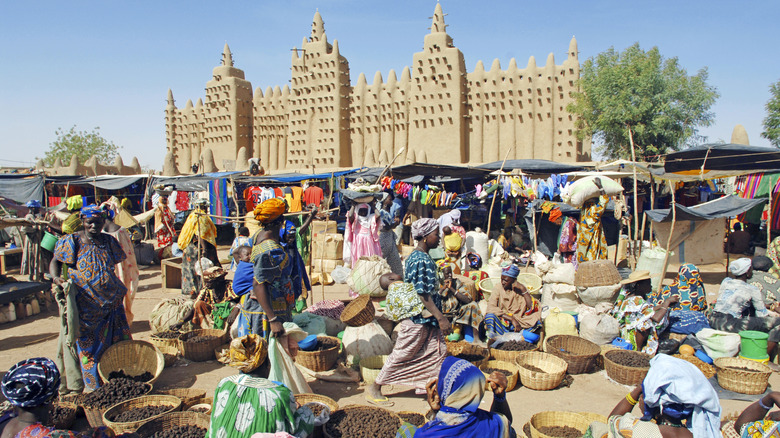 A colorful market scene in Mali with people, baskets, and kiosks.