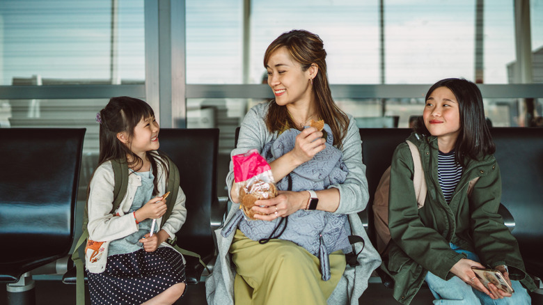 A mother shares a snack with her daughters at an airport