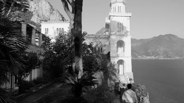 a black and white still of an italian view of a white villa overlooking the sea