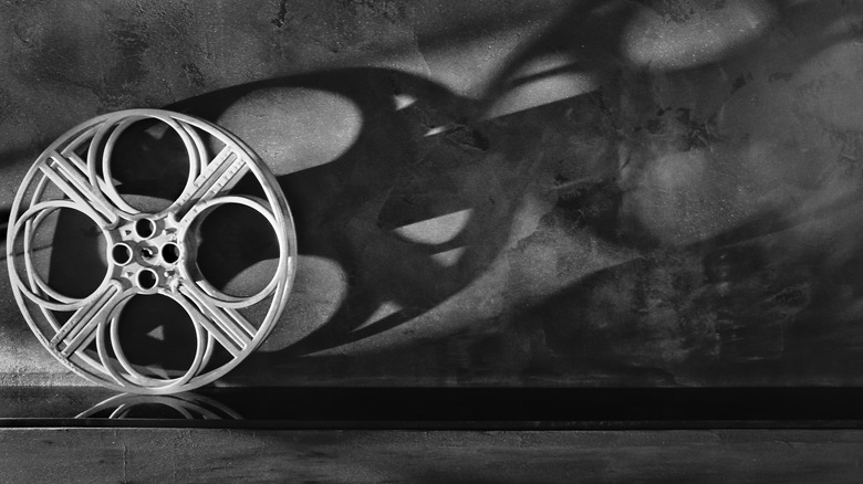 black and white picture of empty film reel against wall