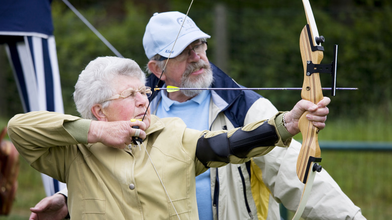 Older man and woman practicing with bow and arrow