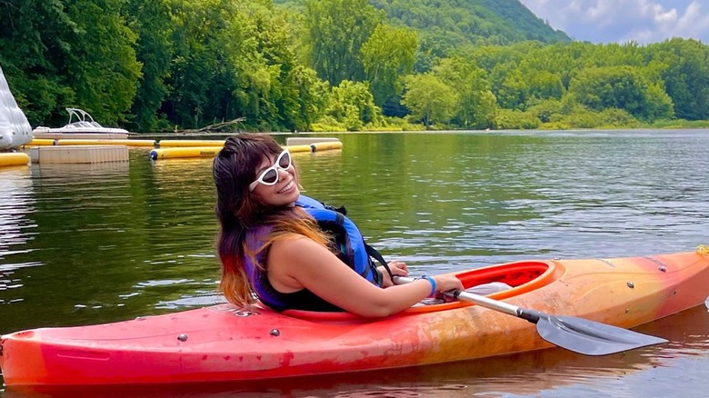 People sitting in lawn chairs and playing on inflatables by lake at Club Getaway