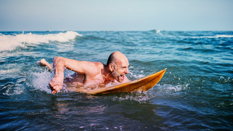 Man paddling in ocean on surfboard