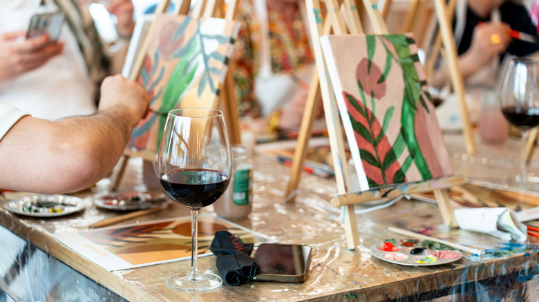 People painting on easels alongside glasses of wine