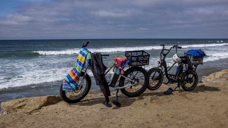 Two electric bikes with beach towels parked in front of Pacific Ocean