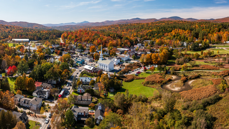 Aerial view of Stowe, Vermont with fall foliage and mountains surrounding buildings in town