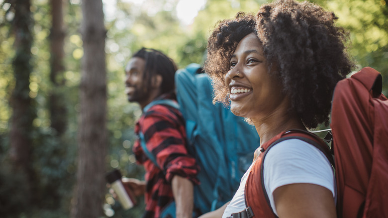 A young black couple hiking through forest.