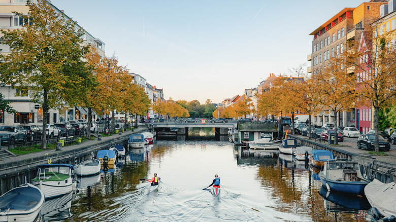 Boats moored along Christianshavns Kanal with colorful historic buildings and autumn foliage in the Christianshavn district.