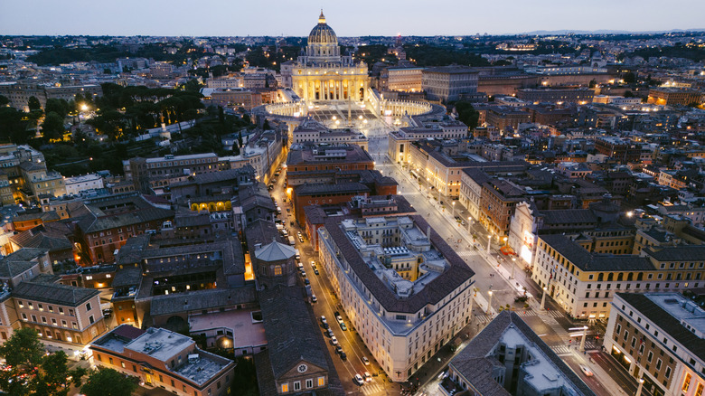Italy, Lazio, Rome, aerial over the rooftops of the city of Rome, St Peter's basilica and Vatican at dusk