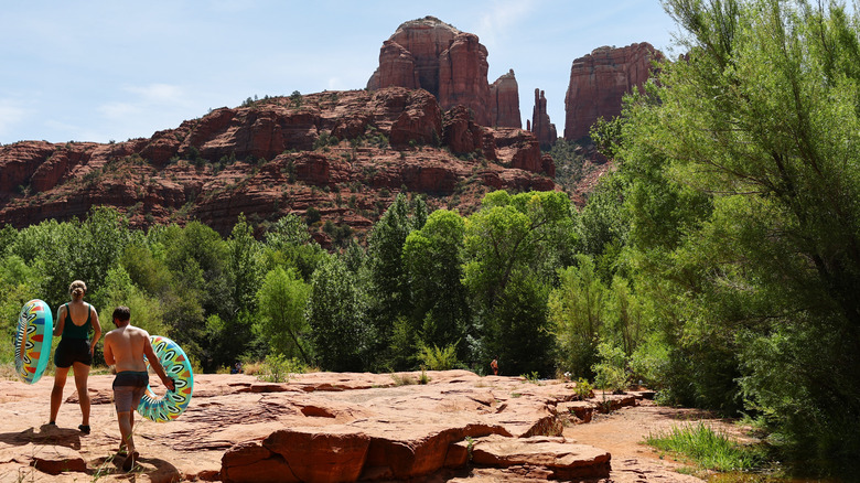 Two people with floats walking alongside Oak Creek near Sedona