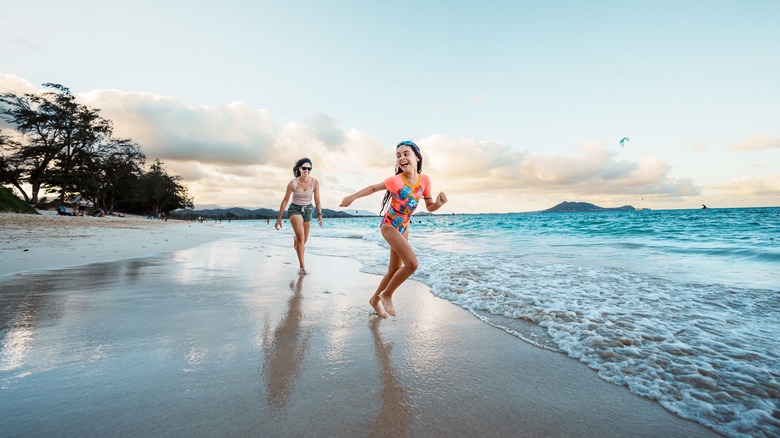 Woman and daughter playing on beach in Hawai'i