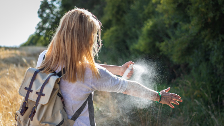Hiker using bug spray