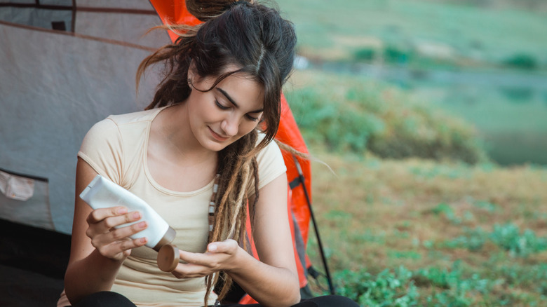 Camper using lotion outside tent
