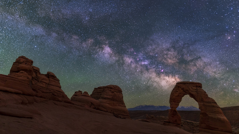 A colorful Milky Way rises behind Delicate Arch in Arches National Park.