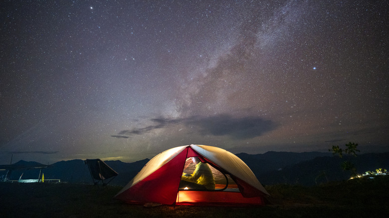 Red tent camping under night sky with stars